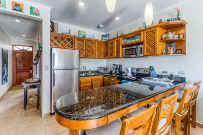 a kitchen with wooden cabinets and a large counter top at La Paloma Blanca D2 in Jacó