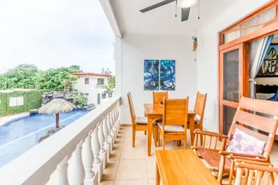 a balcony with a table and chairs and a swimming pool at La Paloma Blanca D2 in Jacó