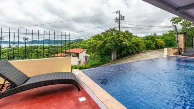 a swimming pool with a chair next to a house at 2 Bedroom Ocean-View Condo with Pool in Playa Flamingo