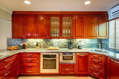 a kitchen with wooden cabinets and a stove top oven at Spacious Open-Concept Condo with Stylish Design, Direct Beach Access & Resort-Style Amenities in Playa Flamingo