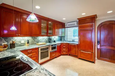 a large kitchen with wooden cabinets and appliances at Spacious Open-Concept Condo with Stylish Design, Direct Beach Access & Resort-Style Amenities in Playa Flamingo