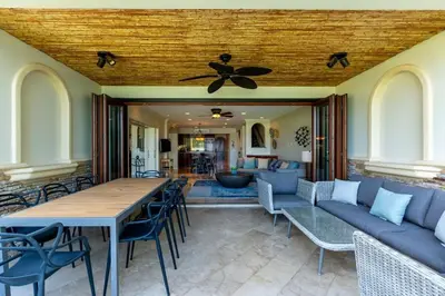 a living room with a ceiling fan and a table and chairs at Spacious Open-Concept Condo with Stylish Design, Direct Beach Access & Resort-Style Amenities in Playa Flamingo