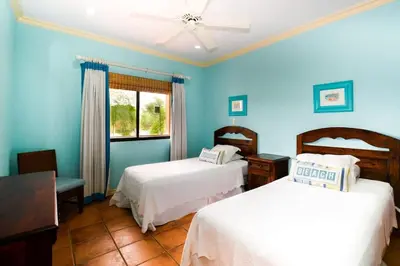 a blue room with two beds and a window at Elegant 3BR Beachfront Condo with Spacious Interior, Ocean-View Terrace & Direct Access to Playa Flamingo in Playa Flamingo