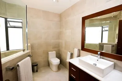 a bathroom with a sink and a toilet and a mirror at Elegant 3BR Beachfront Condo with Spacious Interior, Ocean-View Terrace & Direct Access to Playa Flamingo in Playa Flamingo