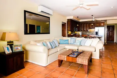 a living room with a white couch and a table at Elegant 3BR Beachfront Condo with Spacious Interior, Ocean-View Terrace & Direct Access to Playa Flamingo in Playa Flamingo