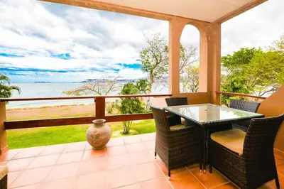 a porch with a table and chairs and a view of the ocean at Elegant 3BR Beachfront Condo with Spacious Interior, Ocean-View Terrace & Direct Access to Playa Flamingo in Playa Flamingo