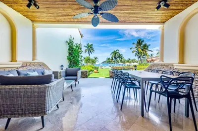 a patio with a table and chairs and a ceiling fan at Stylish Split-Level Condo with a Shaded Terrace, Direct Beach Access, and Resort-Style Community Amenities in Playa Flamingo