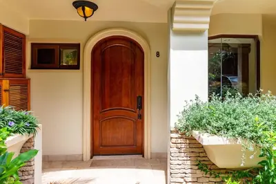 a wooden door on a house with some plants at Stylish Split-Level Condo with a Shaded Terrace, Direct Beach Access, and Resort-Style Community Amenities in Playa Flamingo