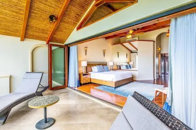 a bedroom with a bed and a living room at Stylish Split-Level Condo with a Shaded Terrace, Direct Beach Access, and Resort-Style Community Amenities in Playa Flamingo
