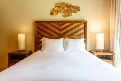 a bedroom with a large white bed with two lamps at Stylish Split-Level Condo with a Shaded Terrace, Direct Beach Access, and Resort-Style Community Amenities in Playa Flamingo