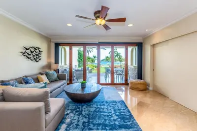 a living room with a couch and a ceiling fan at Stylish Split-Level Condo with a Shaded Terrace, Direct Beach Access, and Resort-Style Community Amenities in Playa Flamingo