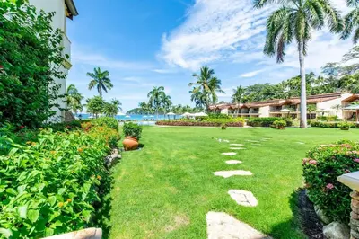 a garden with a lawn with a pathway at Stylish Split-Level Condo with a Shaded Terrace, Direct Beach Access, and Resort-Style Community Amenities in Playa Flamingo