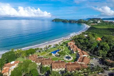 an aerial view of a beach with houses and the ocean at Stylish Split-Level Condo with a Shaded Terrace, Direct Beach Access, and Resort-Style Community Amenities in Playa Flamingo