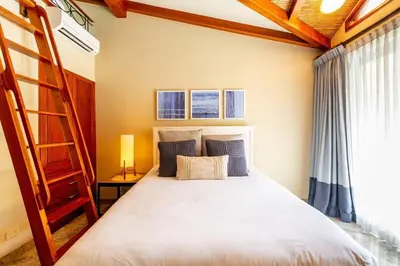 a bedroom with a bunk bed and a ladder at Modern Oceanfront Condo with a Chic Coastal Design, Resort-Style Amenities, and Direct Beach Access in Playa Flamingo