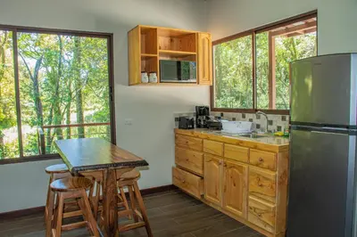 a kitchen with a table and a refrigerator at Green Habitat in Monteverde Costa Rica