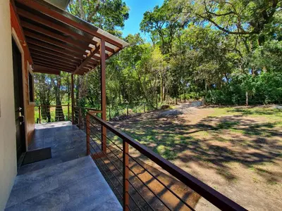 a porch of a house with a fence and trees at Green Habitat in Monteverde Costa Rica