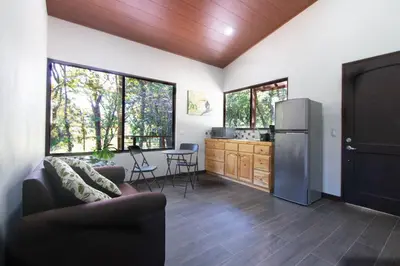 a kitchen and living room with a refrigerator and windows at Green Habitat in Monteverde Costa Rica