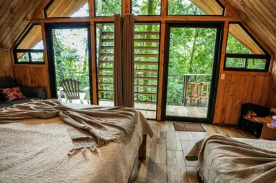 a bedroom with a bed and large glass windows at Tityra Lodge in Monteverde Costa Rica