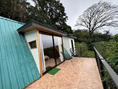 a small house with a deck with a chair on it at Tityra Lodge in Monteverde Costa Rica