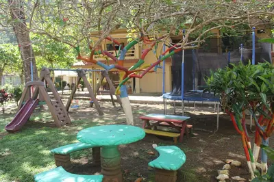 a playground with a slide and a tree at Centro Vacacional Bancosta in Jacó