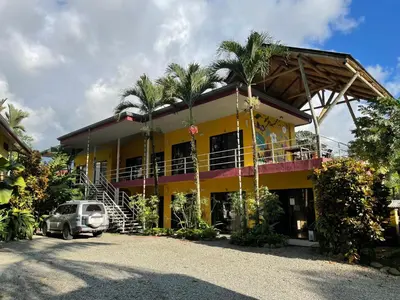 a yellow house with a car parked in front of it at Hotel LUZ de LUNA Bahía Ballena in Uvita