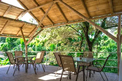 a patio with tables and chairs under a wooden pergola at Hotel LUZ de LUNA Bahía Ballena in Uvita