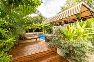 a garden with a wooden deck and a swimming pool at Little Hawaii Avellanas in Playa Avellana