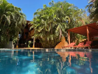 a pool at a resort with palm trees at Mundo Milo Eco Lodge in Playa Junquillal