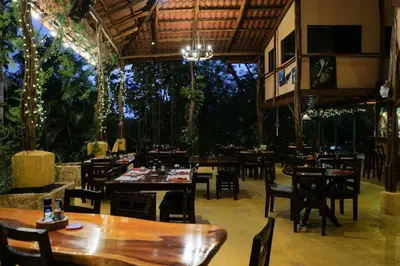 a restaurant with wooden tables and chairs and trees at Mundo Milo Eco Lodge in Playa Junquillal