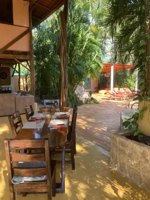 a dining room with a table and chairs and trees at Mundo Milo Eco Lodge in Playa Junquillal