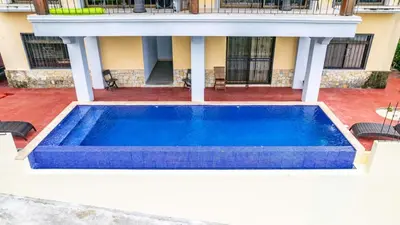 a large blue swimming pool in front of a house at Modern, Immaculate Unit in Flamingo with Spectacular Ocean Views in Playa Flamingo