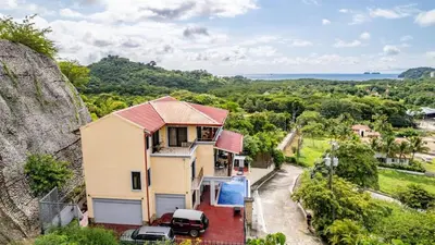 a house on a hill with a car parked next to it at Modern, Immaculate Unit in Flamingo with Spectacular Ocean Views in Playa Flamingo