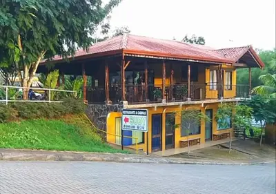 a yellow house with a balcony on the side of the street at Restaurante y cabinas Sudy in Carara