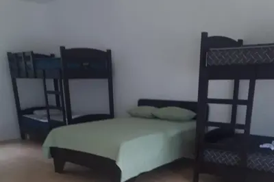 a bedroom with a bed and two bunk beds at Restaurante y cabinas Sudy in Carara