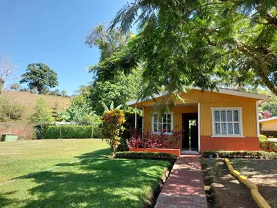 a small yellow house with a grass yard at Restaurante y cabinas Sudy in Carara