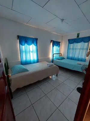 a bedroom with two beds and blue curtains at Restaurante y cabinas Sudy in Carara