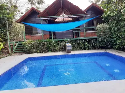 a pool with a hammock and a house at Restaurante y cabinas Sudy in Carara