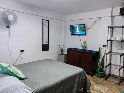 a bedroom with a bed and a tv on the wall at Casa Victoria in Puntarenas