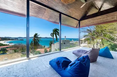 a living room with blue pillows and a view of the ocean at Stunning Home with Brand-New Guesthouse and Oceanview Terrace with Private Swimming Pool & Hot Tub in Playa Flamingo