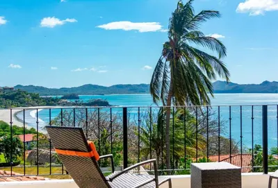 a chair on a balcony with a view of the ocean at Stunning Home with Brand-New Guesthouse and Oceanview Terrace with Private Swimming Pool & Hot Tub in Playa Flamingo