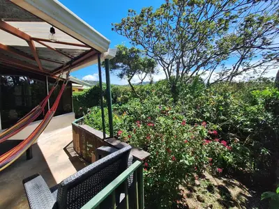 a porch with two benches and flowers and a hammock at Mountain view Monteverde, Cecropia Paradise in Monteverde Costa Rica