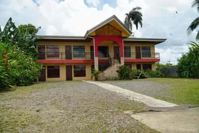 a yellow house with a red trim at Hotel Heliconia Los Chiles in Los Chiles