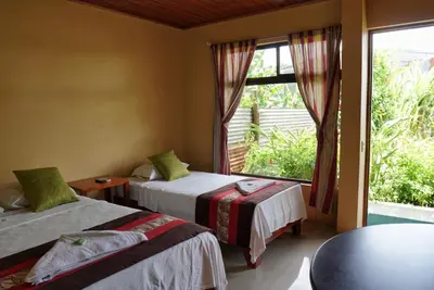 a room with two beds and a large window at Hotel Heliconia Los Chiles in Los Chiles