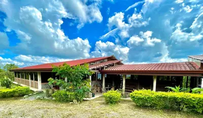 a house with a red roof under a cloudy sky at Casa Lajas - Casa 1 - Hospedaje, Granja y Turismo Rural in Turrialba