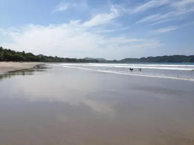 a beach with people walking in the water at Montelaguna Boutique Hotel in Sámara