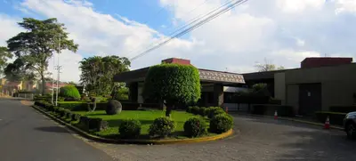 a building with a tree in the middle of a street at Cariari Bed & Breakfast in San José