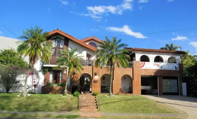 a house with palm trees in front of it at Cariari Bed & Breakfast in San José