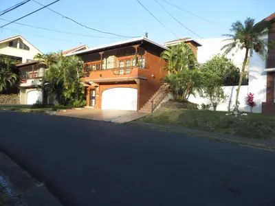 a brown house with a gate and a garage at Cariari Bed & Breakfast in San José