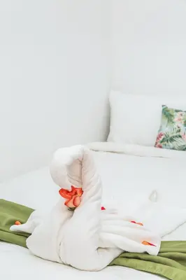 a white towel animal holding a flower on a bed at The Palms At Coco Beach in Coco