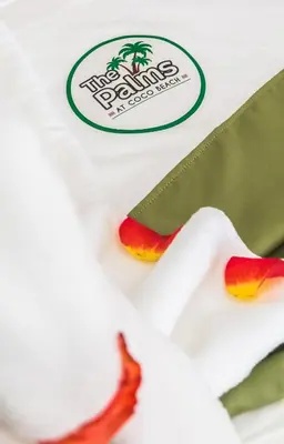 a white shirt with a palm tree logo on it at The Palms At Coco Beach in Coco